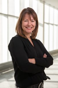 Dr. Lisa Sakside stands in front of a bank of windows.